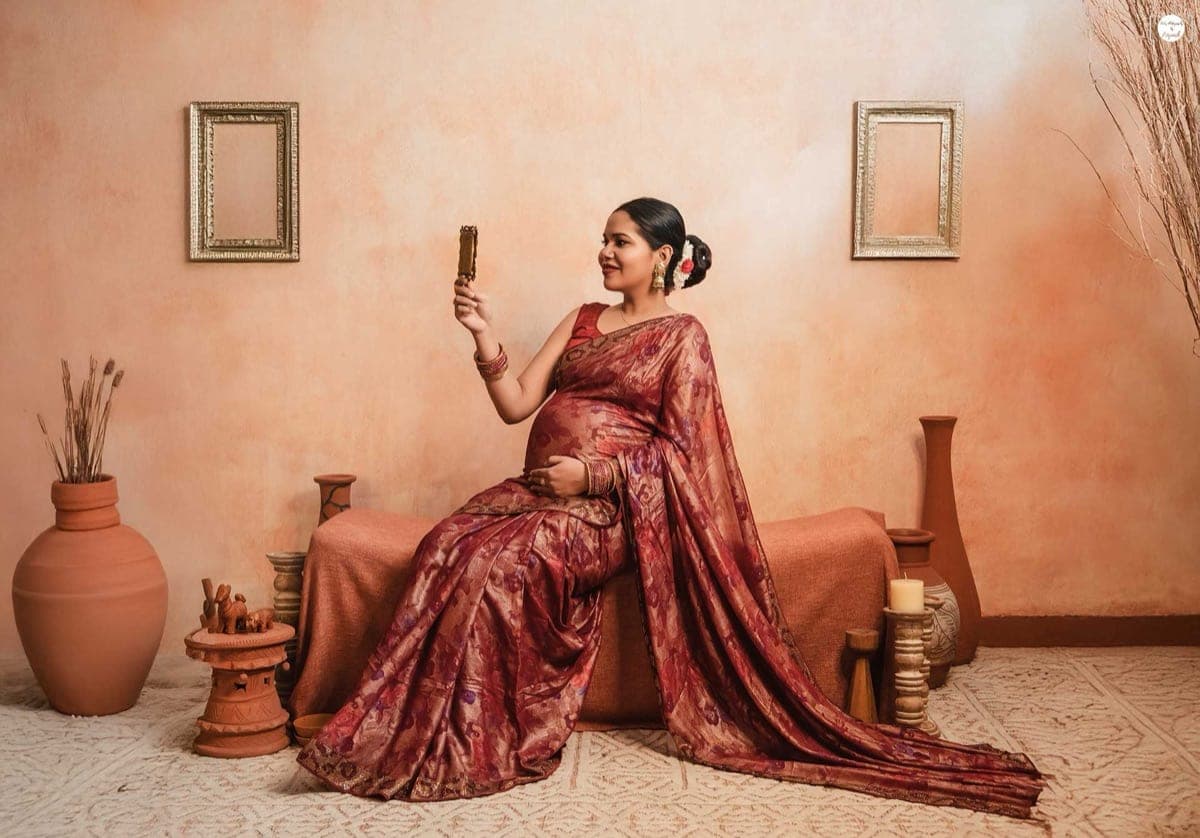 An elegant mother-to-be in a flowing red gown during her maternity photoshoot in South Delhi, by maternity photographer Priyansh Bhardwaj.