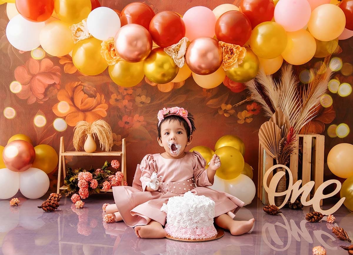Baby enjoying a cake smash photoshoot with balloon birthday setup at a South Delhi studio