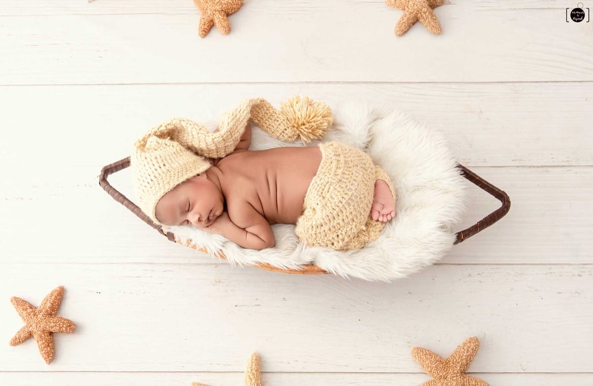 A sleeping newborn wrapped in organic cream-colored linen during a newborn photoshoot in our Delhi NCR studio, by Priyansh Bhardwaj.